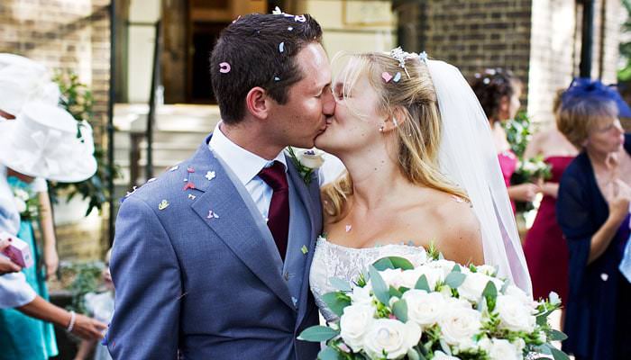 bride and groom kissing with confetti outside htb Wedding Photographer at Holy Trinity Brompton Church and Ognisko (The Polish Club), London for Victoria and Jodey