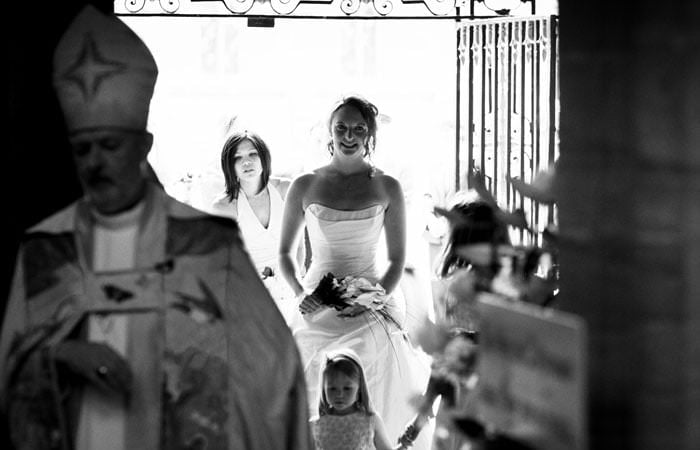Wedding photograph in black and white of Rosie entering Sherborne Abbey, Dorset Wedding Photographer for Rosie & Mark at Sherborne Abbey, Dorset