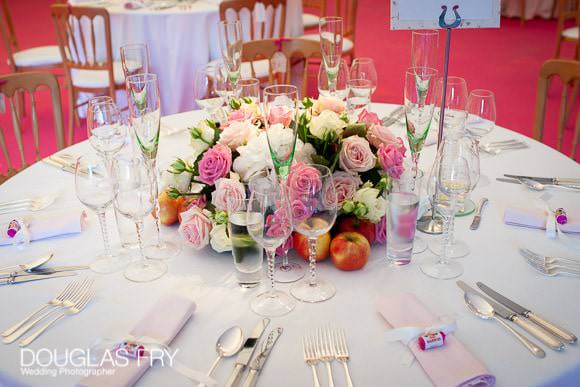 Pink flowers on wedding breakfast tables in marquee