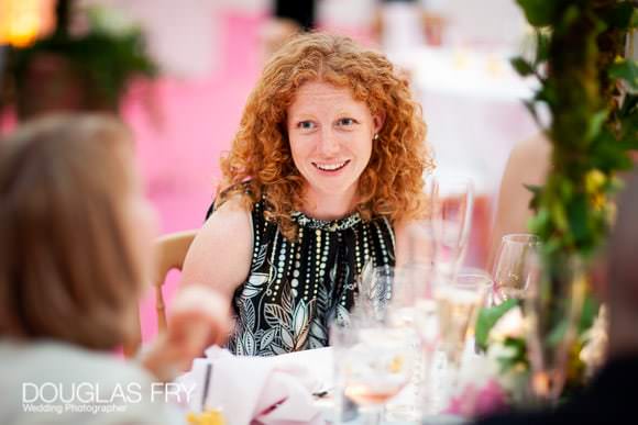 Wedding photography of guests at tables - featuring pink carpet behind