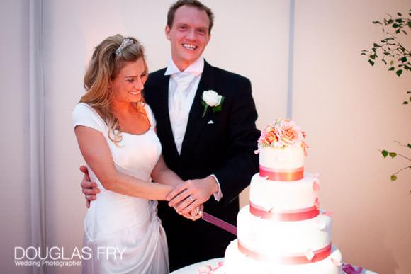 Cutting the cake - wedding cake with pink flowers and tiers