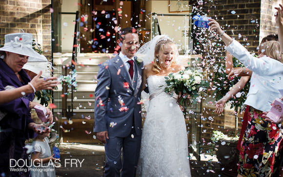 wedding photograph capturing confetti being thrown as couple leave the church steps at HTB