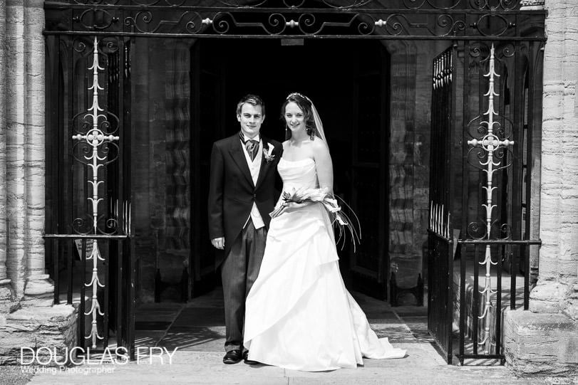 Bride and groom standing in front of Sherborne Abbey in Dorset - black and white photograph