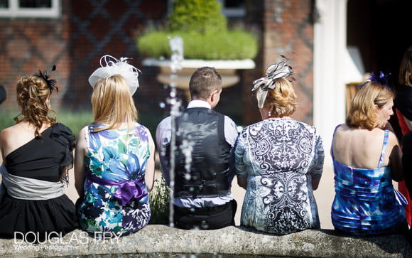 Guests sitting on fountain edge at fulham palace during wedding reception