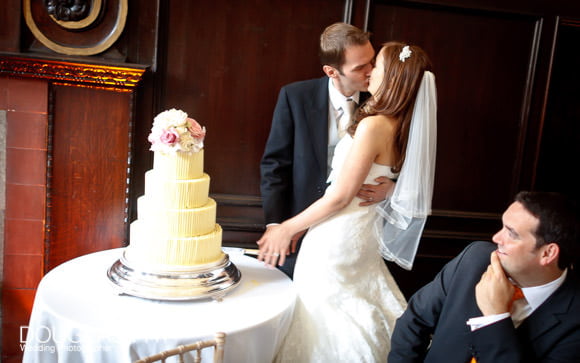 wedding photograph of bride and groom kissing after cutting the wedding cake