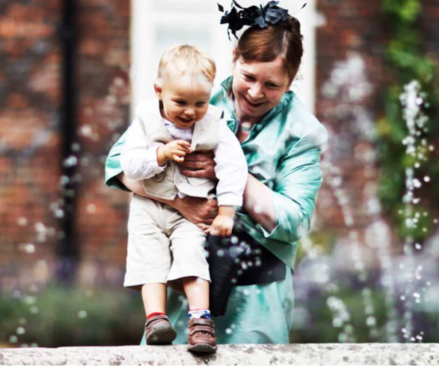 baby next to fountain during wedding reception at Fulham Palace in London - wedding photograph by Douglas Fry