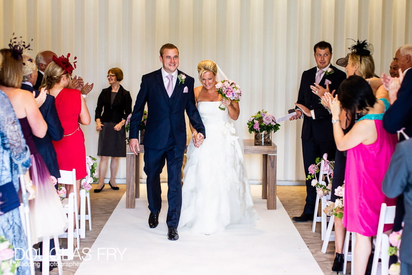 Couple walking down aisle after wedding ceremony at Coworth Park
