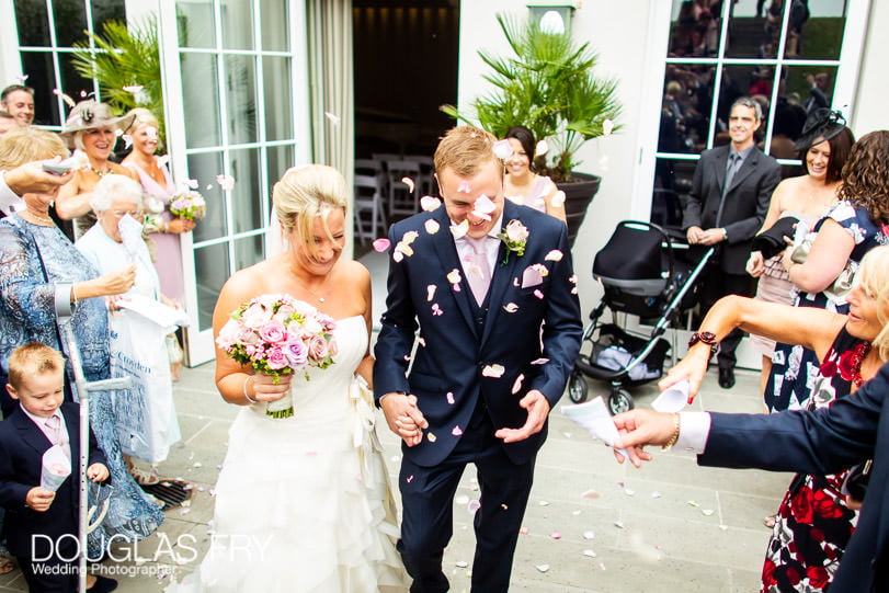 Confetti being thrown photographed during wedding at Coworth Park
