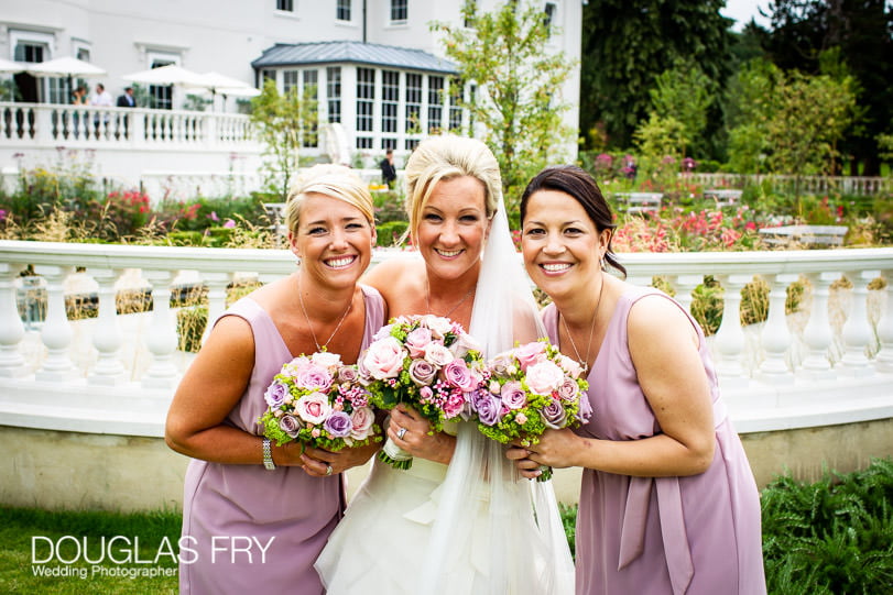 Bride with bridesmaids photographed in front of Coworth Park during wedding reception