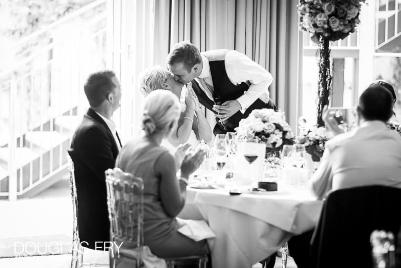 Bride and groom kissing during wedding speeches