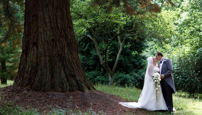 Bride and groom kissing outside under a tree in Cambridgeshire