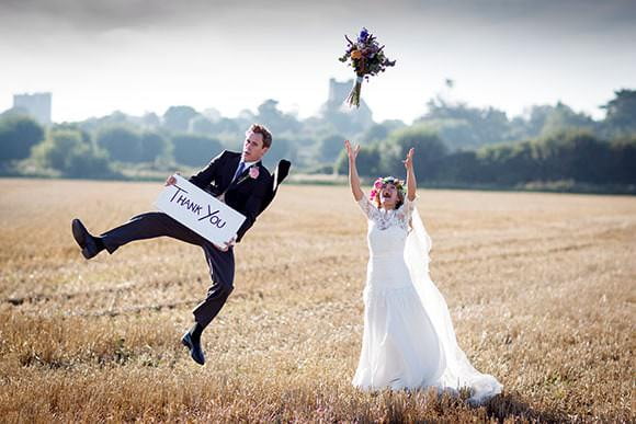 Photograph of bride and groom in field - country wedding with thank you sign
