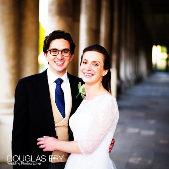 The bride and groom photogrpahed in colour between the colonades at the Admiral's House - outside at Greenwich