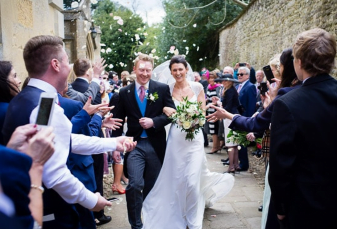 Bride and groom leaving church in Woodstock, Oxfordshire through confetti