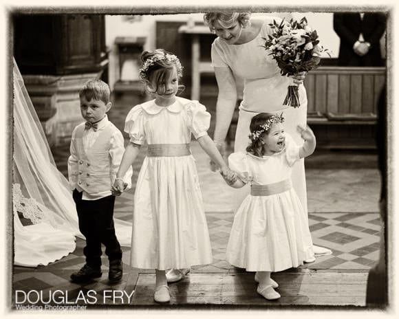 Wedding Photographer Woodstock and Blenheim Palace in Oxfordshire 3 Bridesmaids and page in church with one waving to the congregation