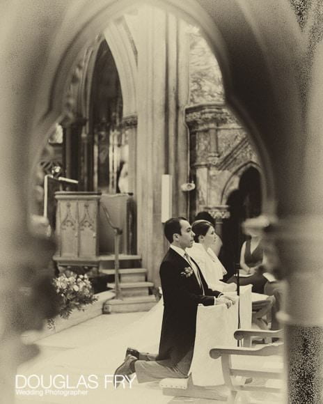 Photograph of bride and groom in Farm Street Church, Mayfair at alter in black and white