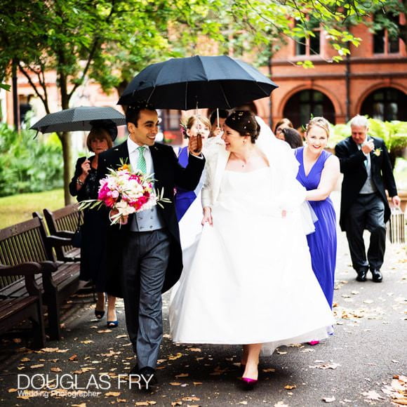 Bride and Groom walking with umbrella in London