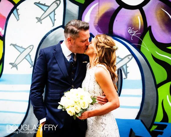 Laura and Andy's Wedding Photographed at Soho Hotel and the Union Club 8 Couple kissing in front of London mural / graffiti