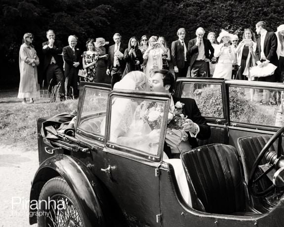 Bride and groom leaving the guests for the reception in vintage car
