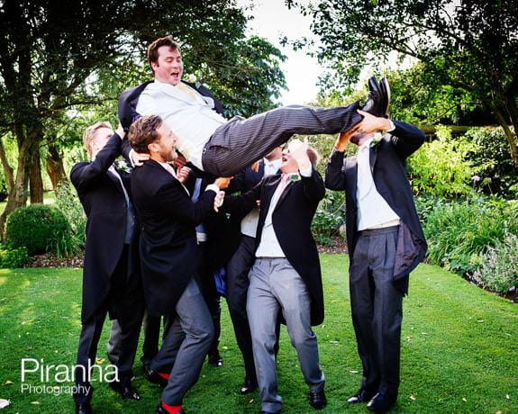 Ushers and groom photographed holding groom aloft