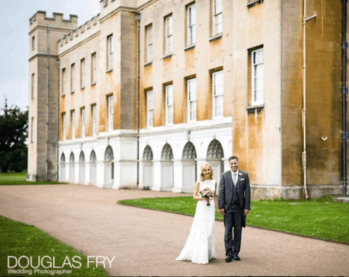 Exterior of Syon Park with bride and groom walking arm in arm during wedding