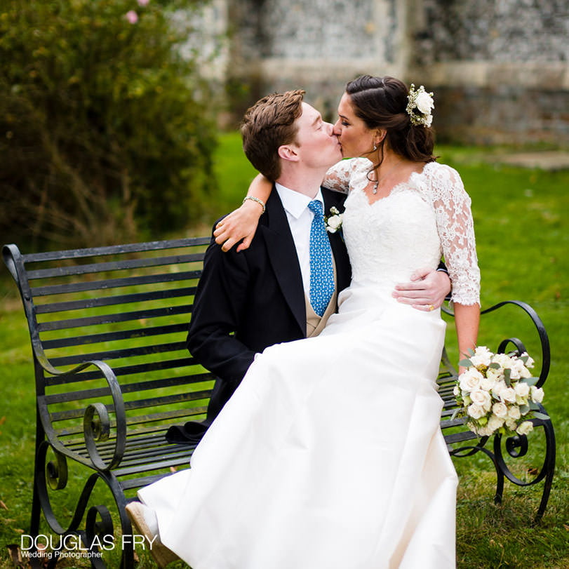 Hampshire Wedding Photographer - Wedding Photography taken last Saturday 1 couple kissing sitting on bench outside church after wedding in Hampshire