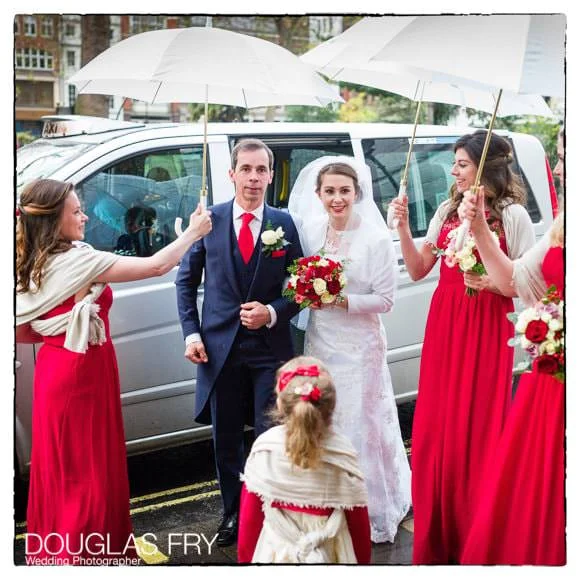 In and Out Club Wedding Photographer (Naval and Military Club) for Charlotte and Robert 1 Bride and father arriving at Soho church in London with umbrellas