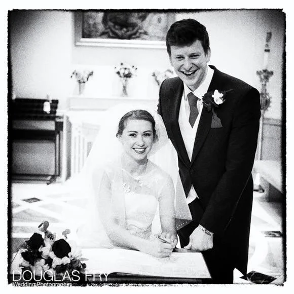 In and Out Club Wedding Photographer (Naval and Military Club) for Charlotte and Robert 3 Bride and groom in black and white signing the register in Church