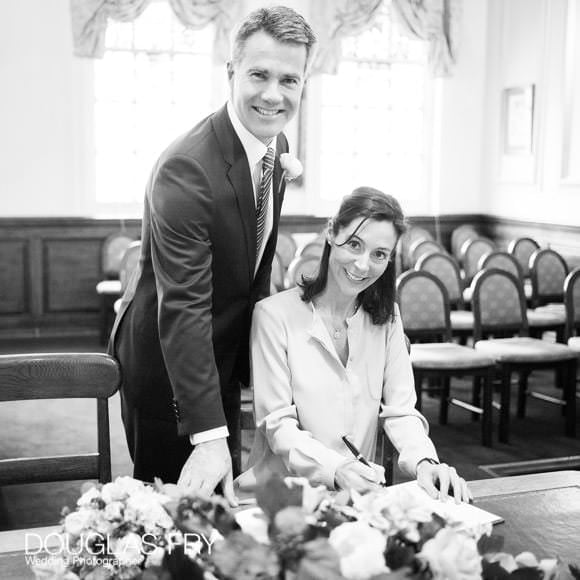 Black and white photograph of couple signing register in Oxford Register Office