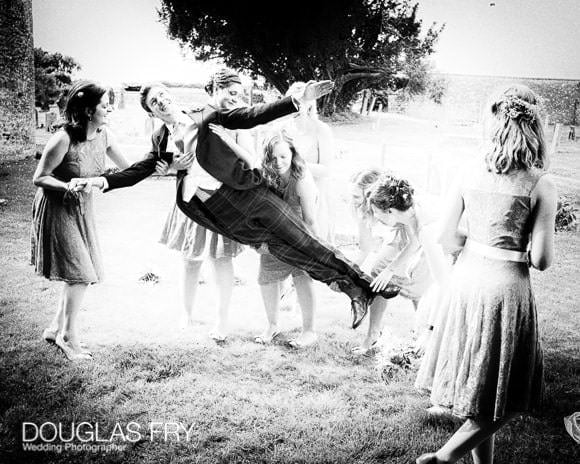 Groom with bridesmaids in front of Gloucestershire church