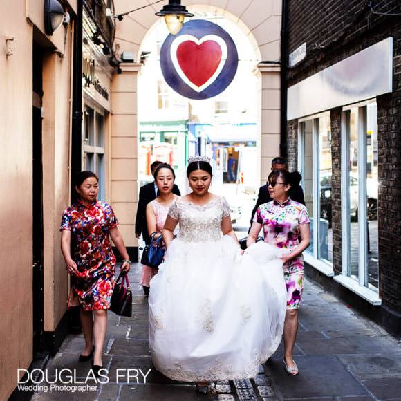 Bride walking through Greenwich Market beneath sign of heart