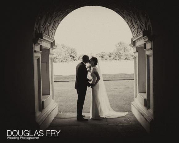 Couple pictured kissing under arch in black and white at Syon Park