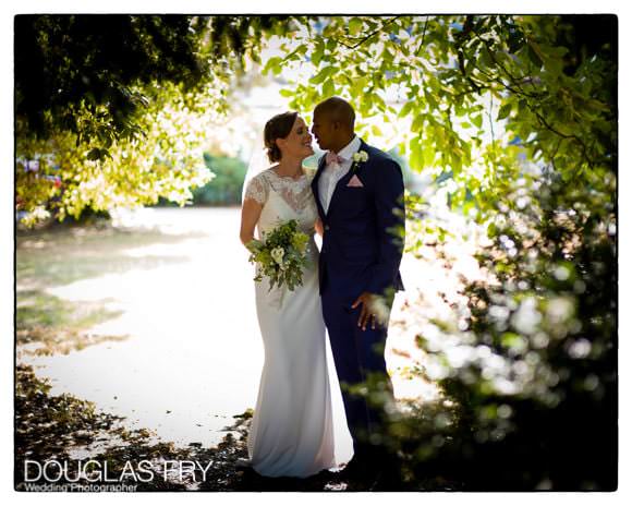Bride and groom under trees in Syon gardens during wedding reception