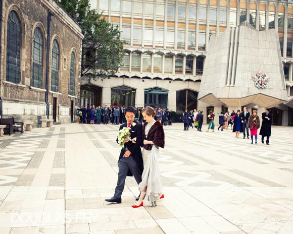 Bride and groom photogrpahed in front of St Lawrence Jewry walkibng through London