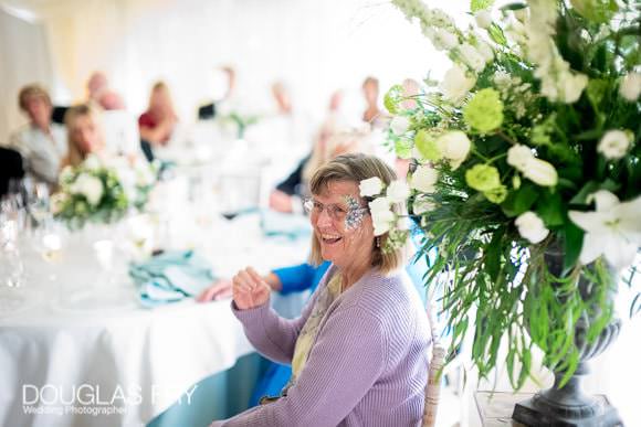 Guests listening and laughing at speeches in marquee