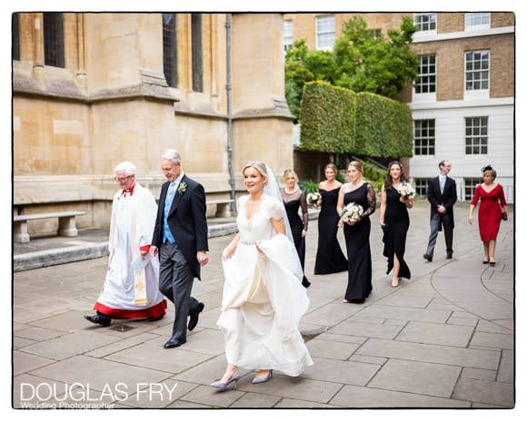 Bride with father and bridesmaids walking towards entrance to Temple Church