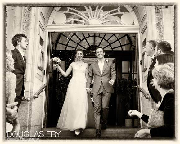 Wedding photograph on steps of Chelsea Register Office after ceremony with confetti and friends and family