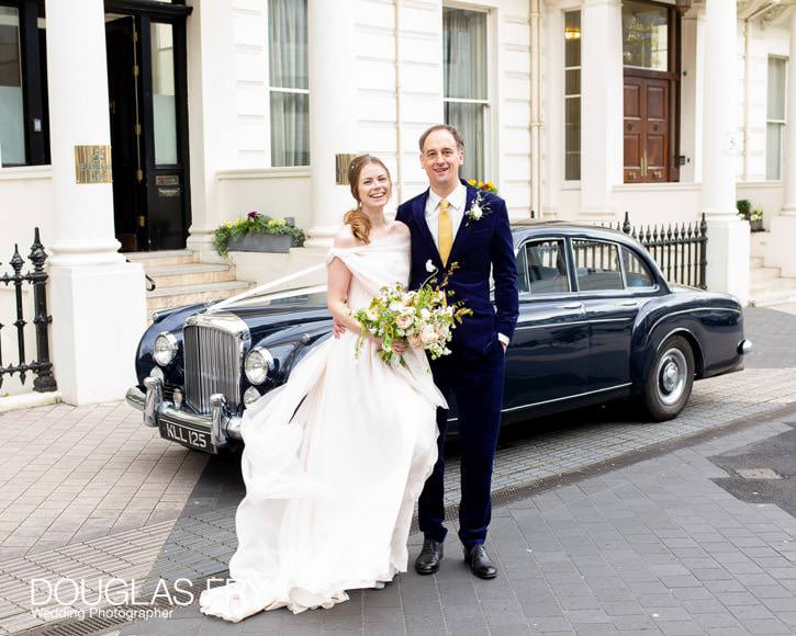 wedding couple pausing for photography outside Ognisko in London with the fabulous Bentley car