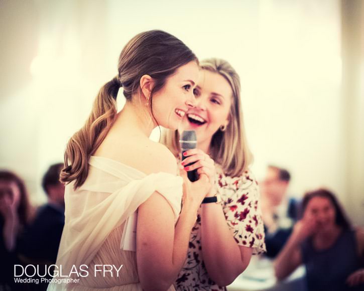 The bride and a friend from school share a fun memory with the guests