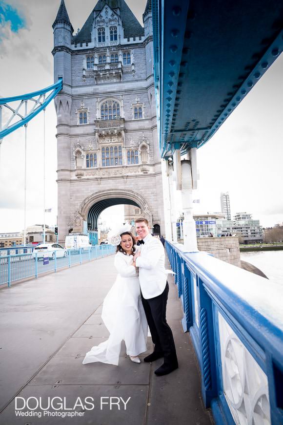 wedding couple pause for portraits on Tower Bridge, London before going in for service