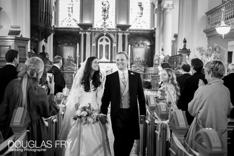 Black and white wedding photograph of couple walking down aisle i hampstead parish church