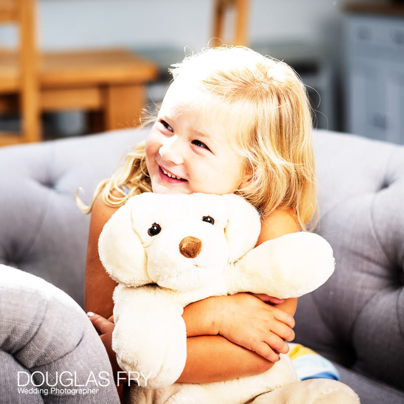 Girl with teddy on sofa at home during family photo shoot