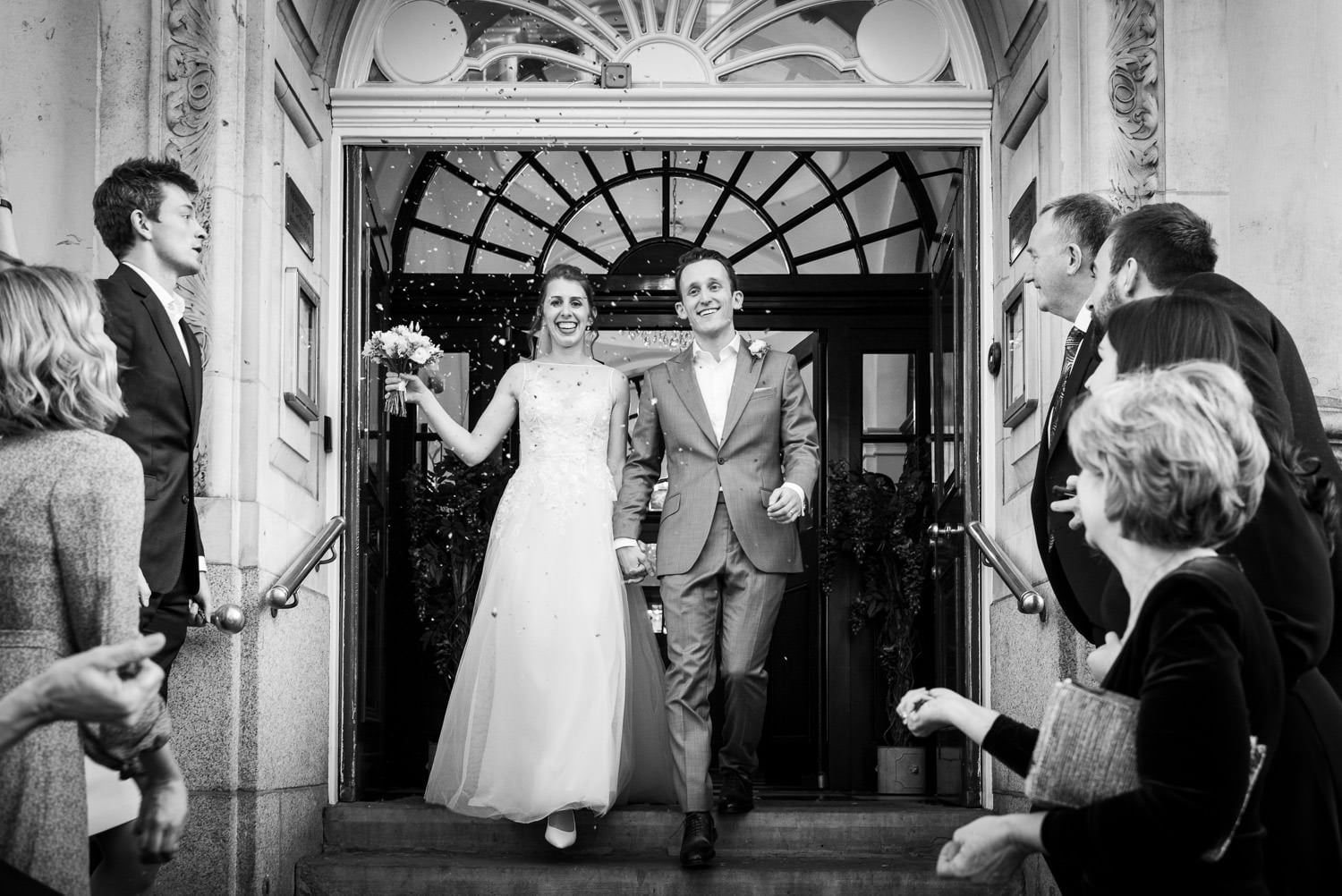 Couple during wedding at Chelsea Register Office photographed on the steps with confetti