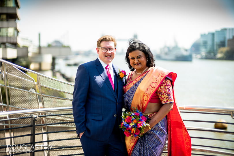 Bride and groom photographed together by the Thames in London