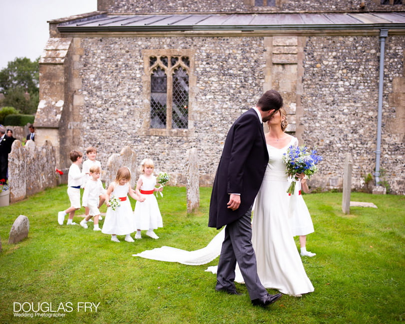 wedding photograph of couple with bridesmaid and pages outisde church.