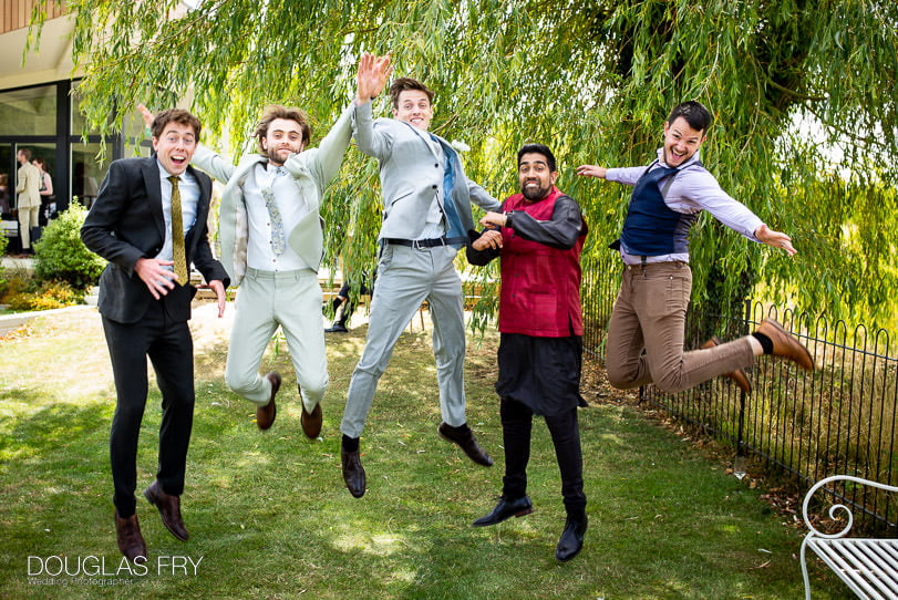 Fun wedding photograph of groom and ushers jumping