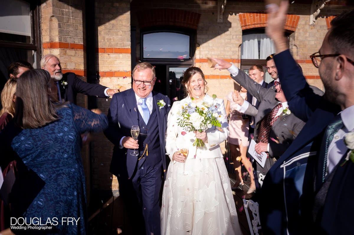 The bride and groom with confetti after the wedding photographed by Douglas Fry